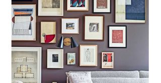 Navy blue living room wall with lots of framed artwork to show how to make a home feel cosy
