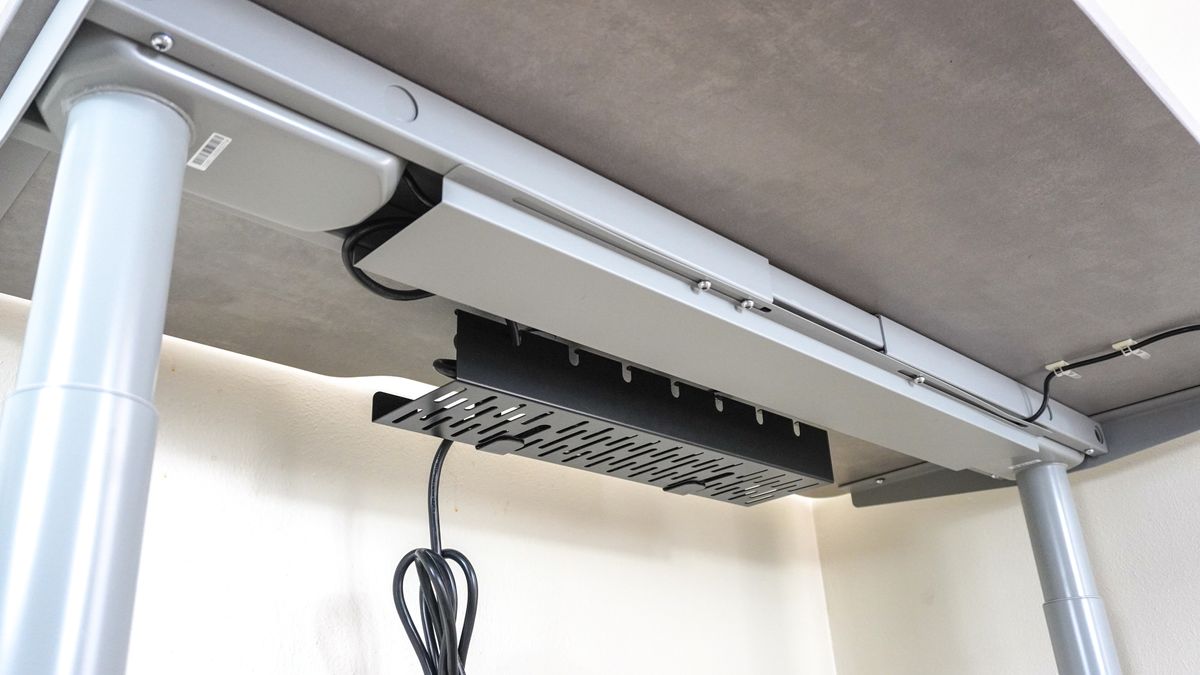 An under desk picture showing off the Hinomi S1 standing desk's cable cover with a cable management tray from FlexiSpot at the back of the desk