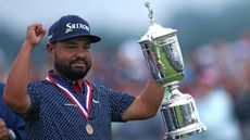 JJ Spaun raises his right fist up to the sky while holding the US Open trophy in his left