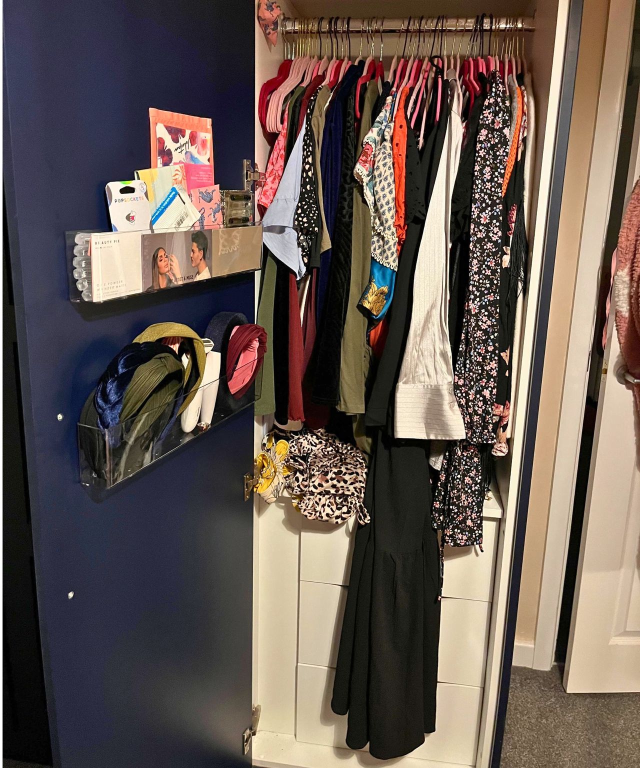 Closet before. open closet looking rammed with clothes and long items hanging out over the front of the built in drawers