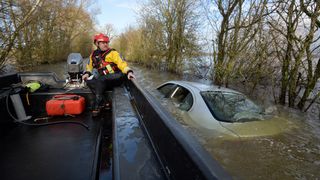 A policeman on a boat looks at a car submerged on the side of a flooded road leading into the cut-off village of Muchelney in Somerset, southwest England, on January 26, 2014. A local council