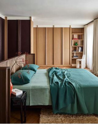 bedroom with green bedding and wood wardrobes