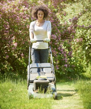 A woman mowing the lawn in the sunshine