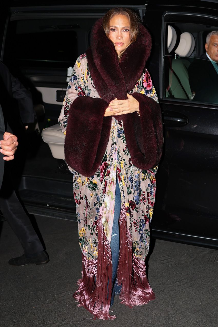 Jennifer Lopez wearing a long, opulent burnout velvet coat with a crop top and distressed jeans in Milan during MFW S/S 27