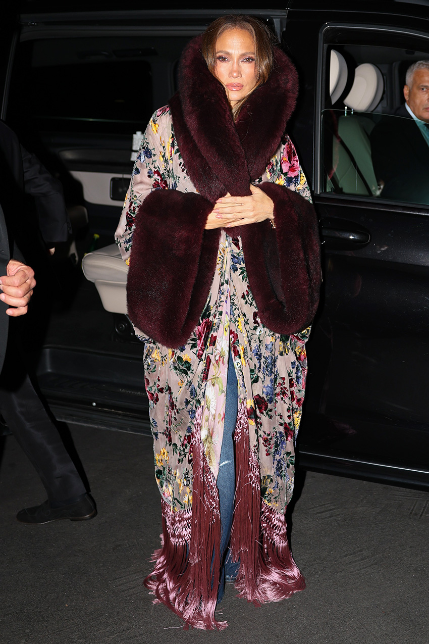 Jennifer Lopez wearing a long, opulent burnout velvet coat with a crop top and distressed jeans in Milan during MFW S/S 27
