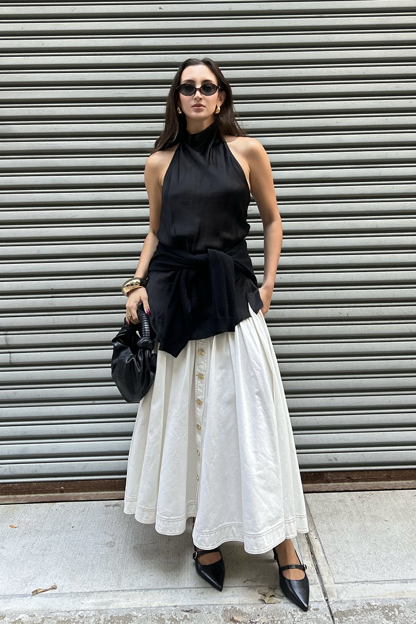 A woman wearing black halter top and white skirt