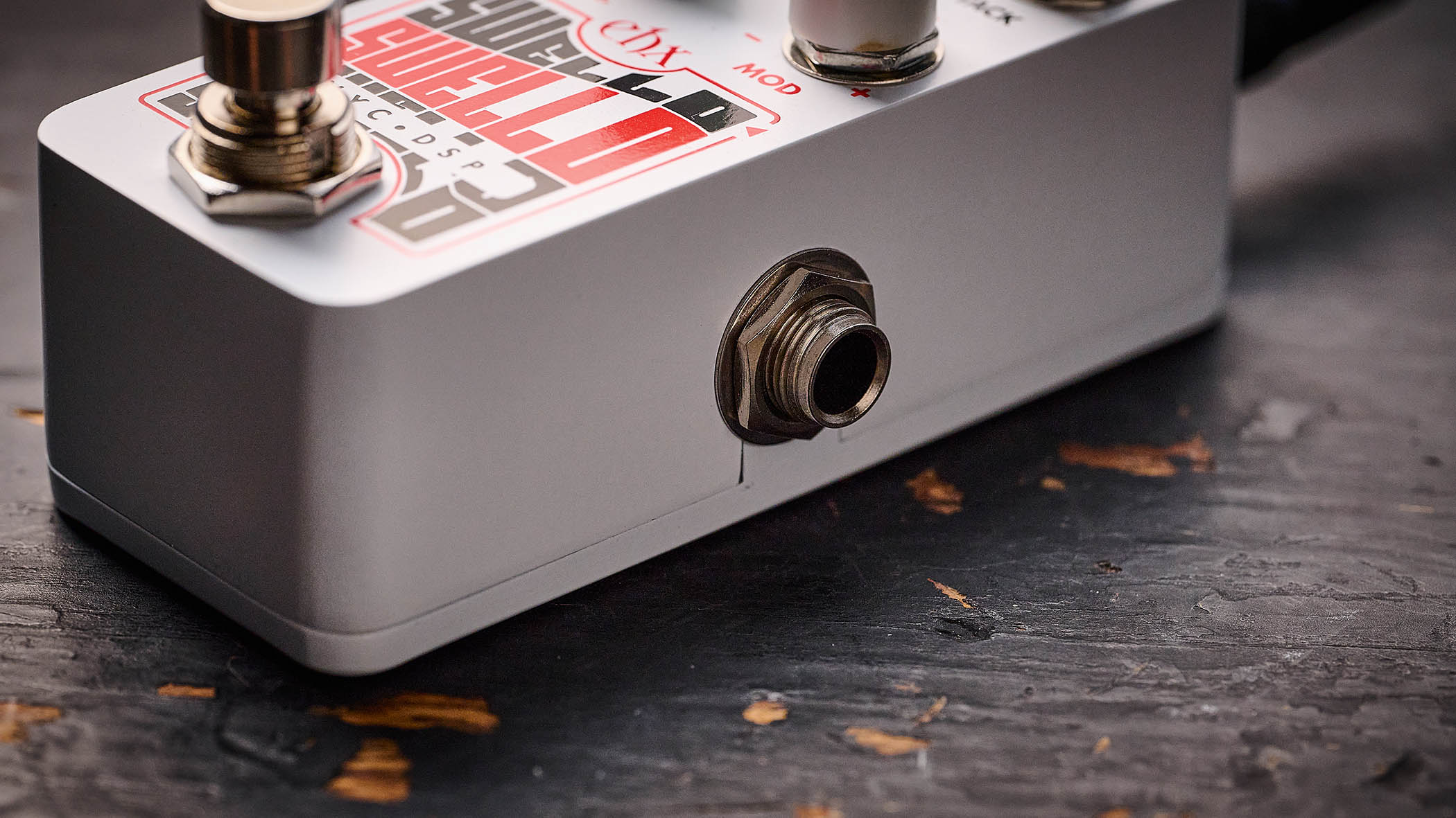 Electro-Harmonix Pico Swello: the compact mini-pedal is finished in white and has black and white text, four knobs, and is photographed against a distressed wood floor.
