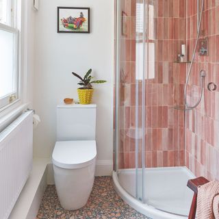 Bathroom with white toilet and a shower cubicle with pink tiles