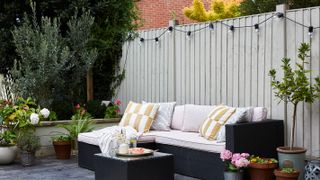outdoor seating area with pale blue painted fence and fairy lights