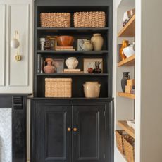 A living room with an alcove with open shelving filled with curated decor and storage baskets