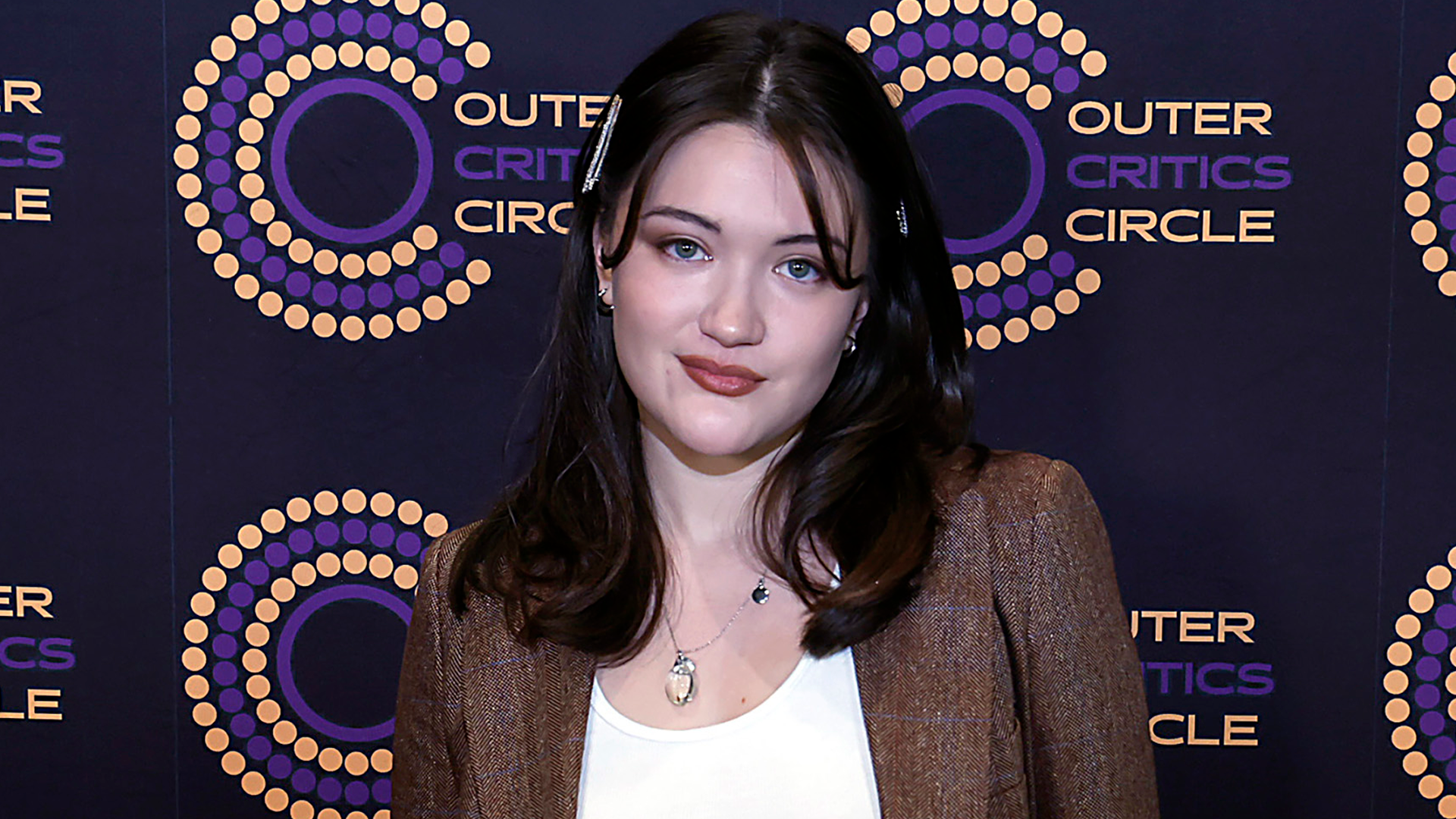 Isa Briones styled dark, low-rise jeans with a white tank top, brown blazer, and matching pumps