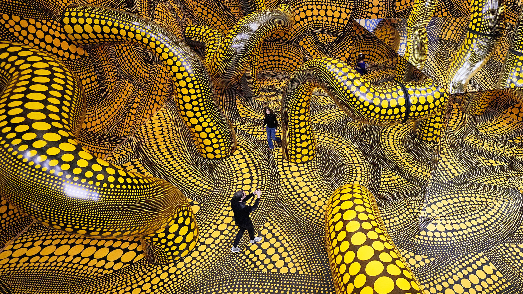 People walk through Yayoi Kusama's 'Infinity Mirrored Room' art installation at the Museum Ludwig in Cologne, Germany