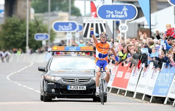 An exultant Reus comes to the line as the peloton appears in the distance