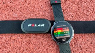 The Polar Vantage V3 and Polar H10 sitting on a track, with the watch showing heart rate zones.