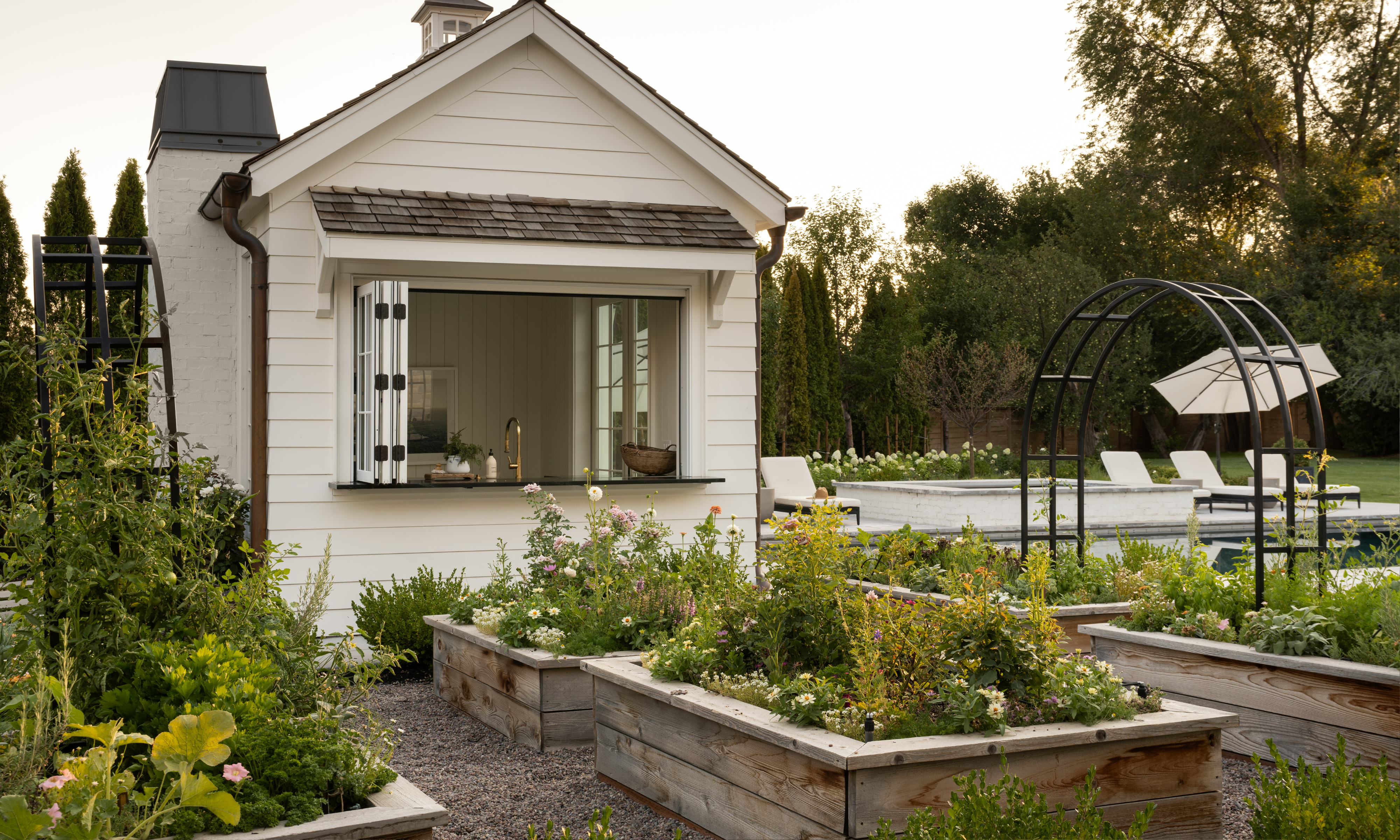 Wooden raised beds full of plants, with black metal arches joining two of them