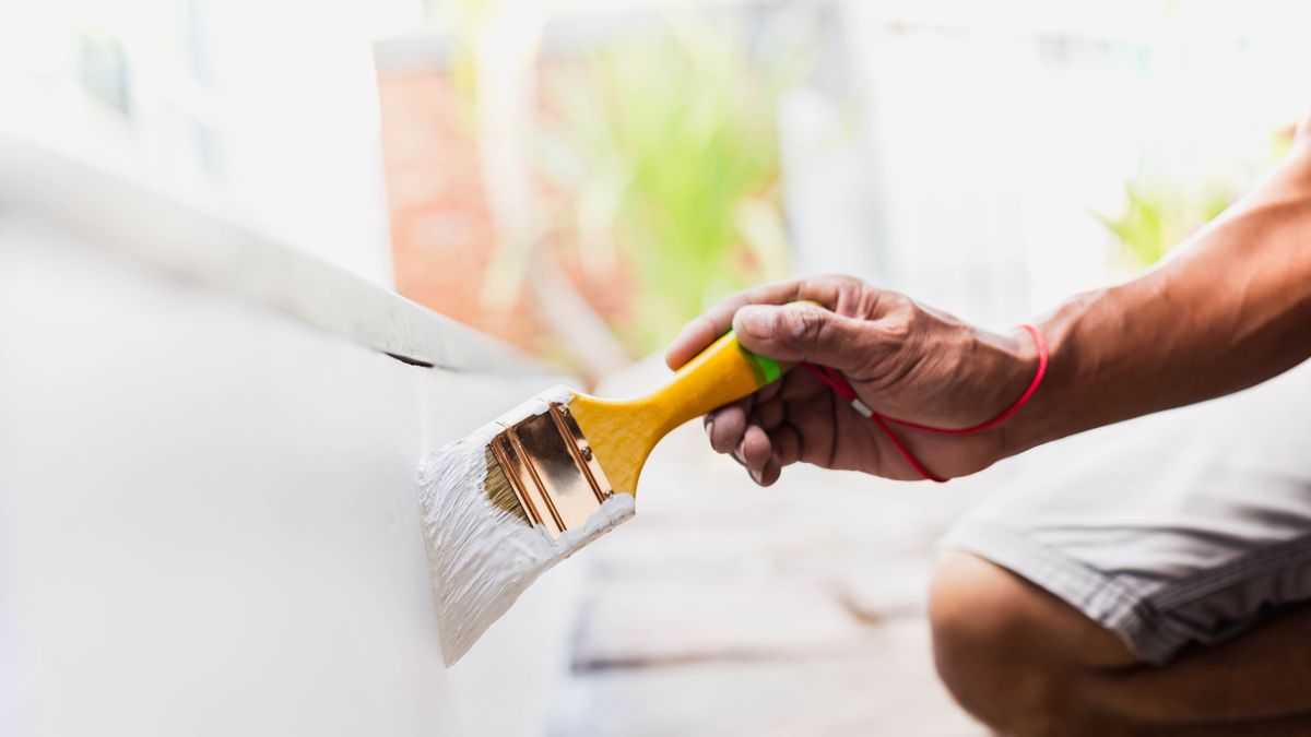 Man painting exterior wall white