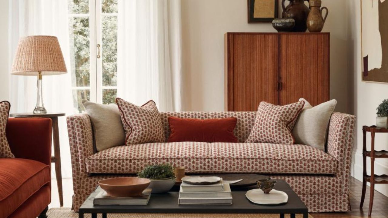 neutral living room with a red and neutral patterned sofa with mid century furniture