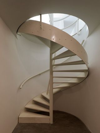 A powder-coated steel spiral staircase heads down to the service floor