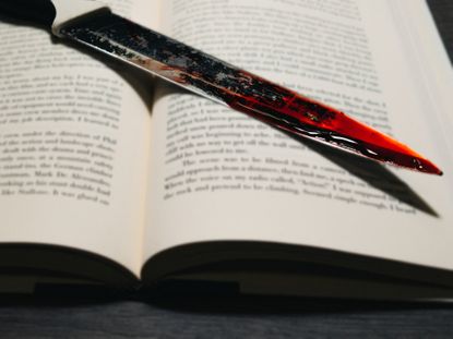 Vignetted image of a bloody kitchen knife on a book 