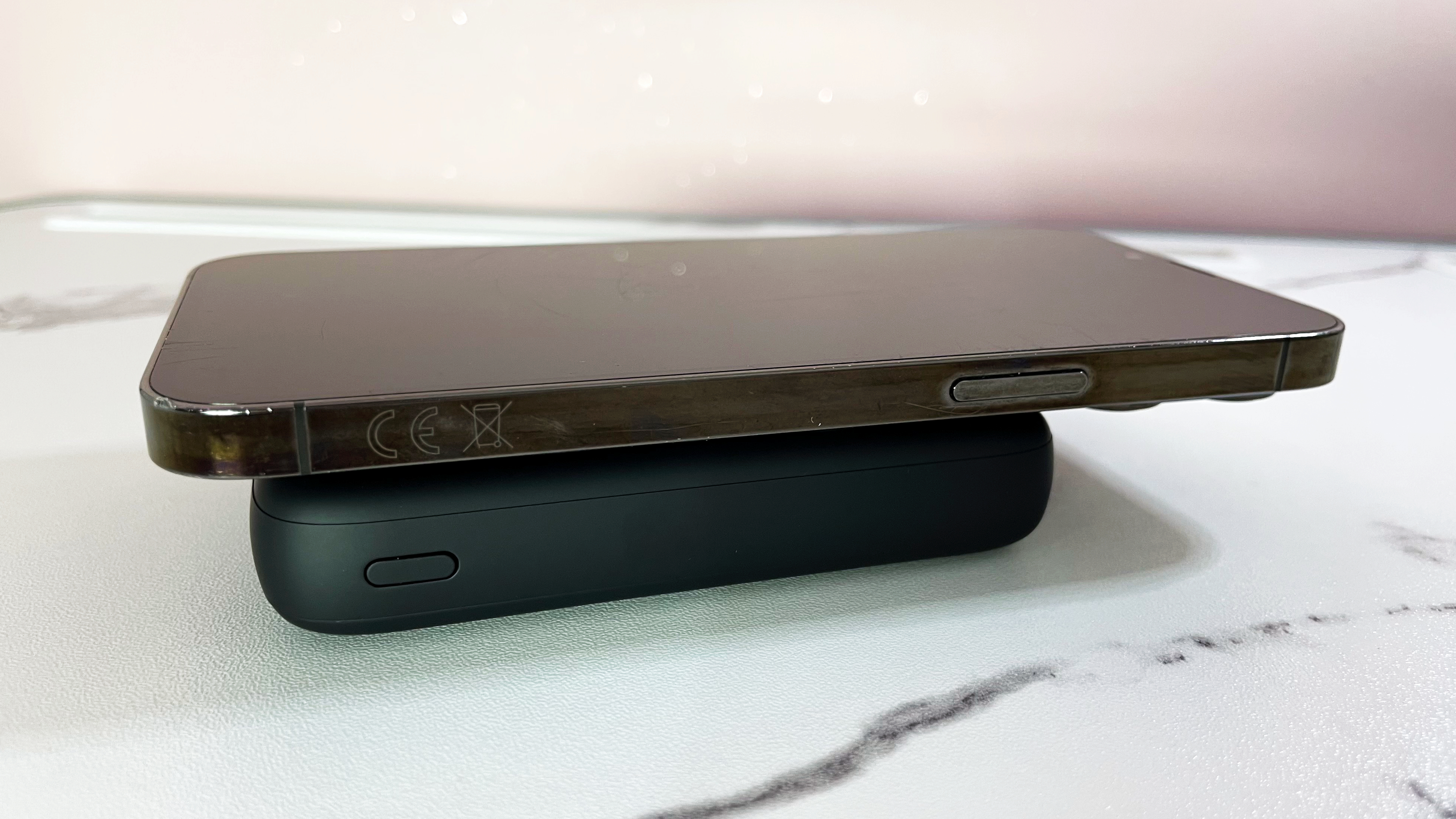 An iPhone is charging on the INIU B43 power bank which sits on a marble-effect surface.