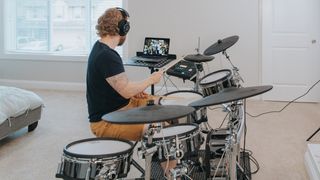 Man plays along to a Drumeo lesson on his electronic drum set