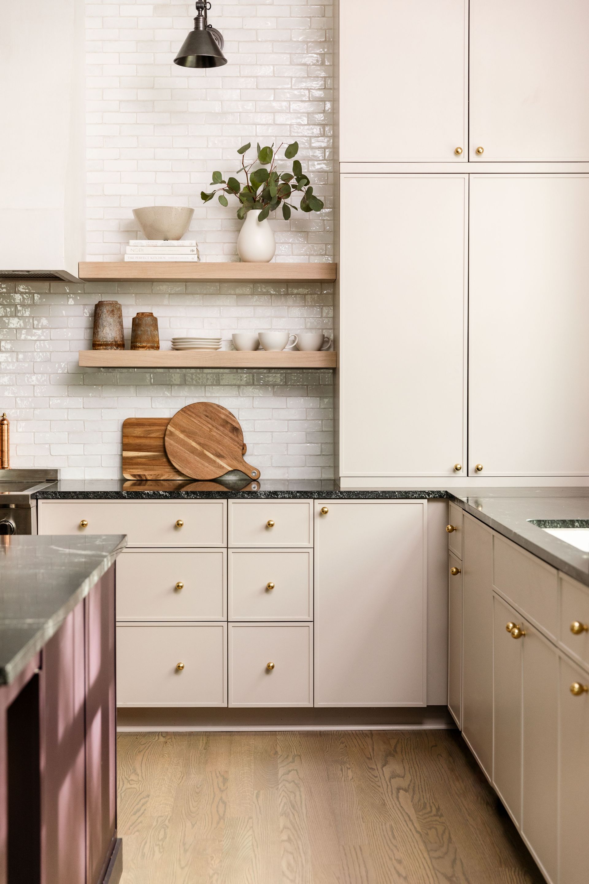 kitchen with pale pink cabinets and brass handles and white tiles