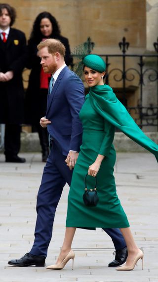 Prince Harry and Meghan Markle, wearing an emerald green gown and matching hat
