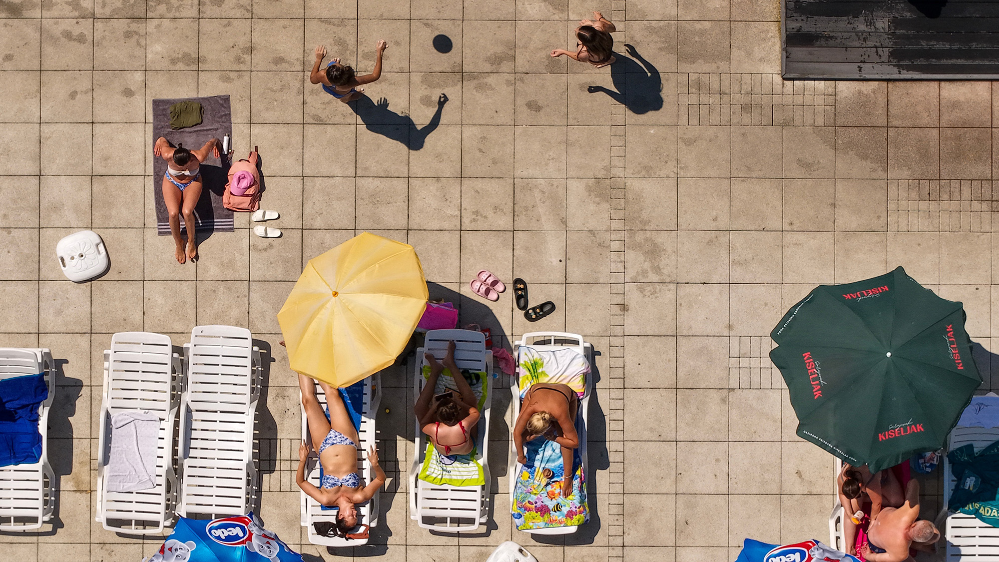 People sunbathe and children play at the Dobrinja public pool in Sarajevo, Bosnia