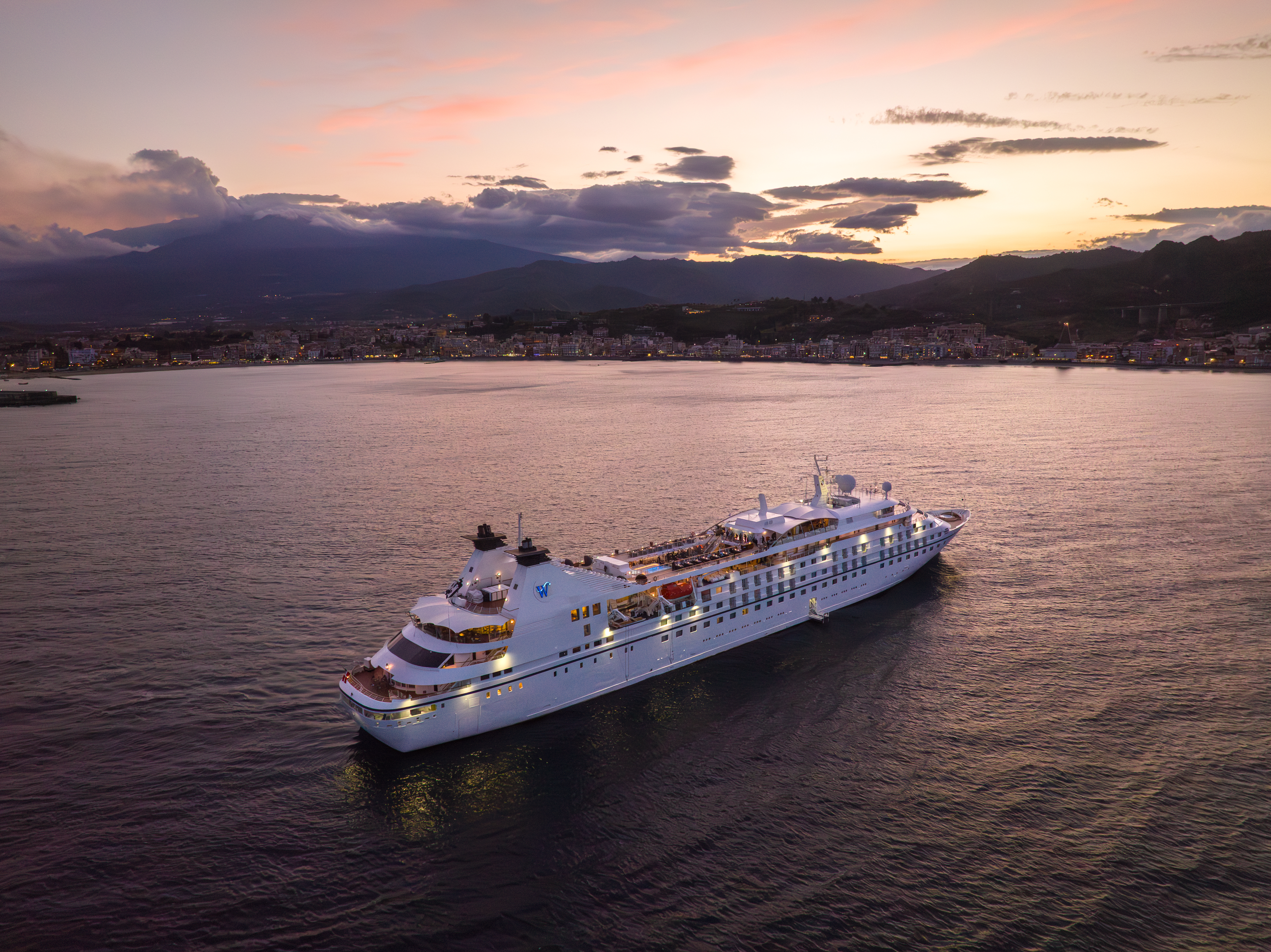 A Windstar Cruise ship at sunset glides on the water