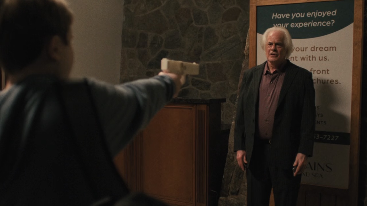 Boy holding gun up and shooting Stacy Crystals in The Chair Company Season 1 finale