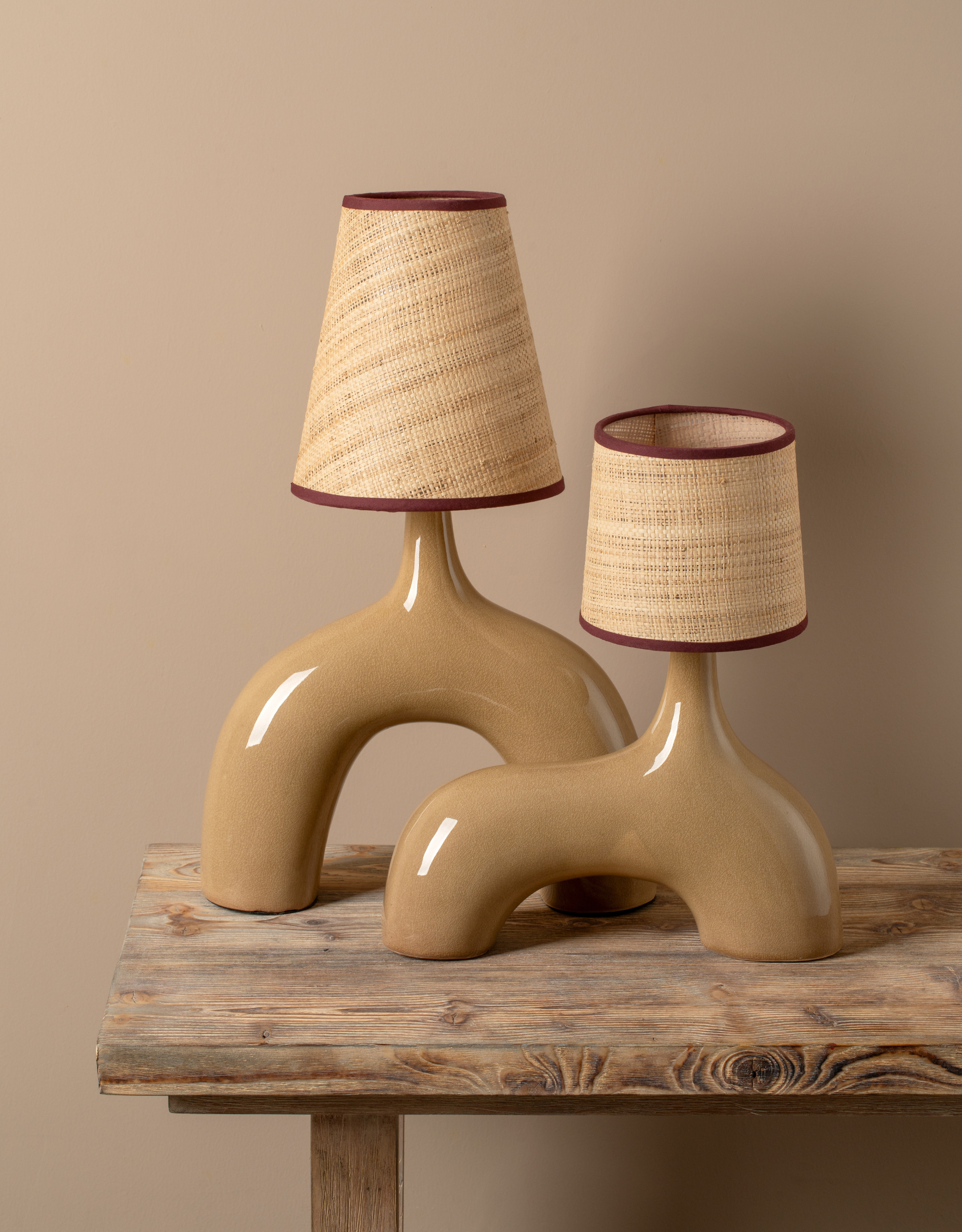 A pair of table lamps with glossy light brown bases and woven shades with maroon hems from lights&amp;amp;lamps