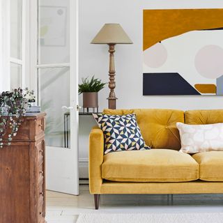 mustard sofa with large abstract artwork and wooden table lamp