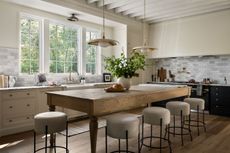 A neutral kitchen with a large kitchen island with a vase of foliage in the middle