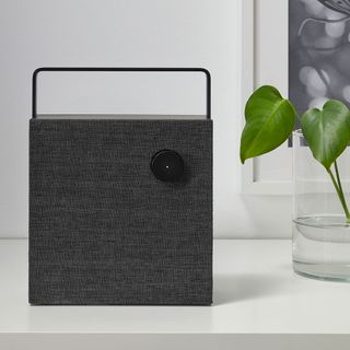 white table with black bluetooth speaker and glass plant