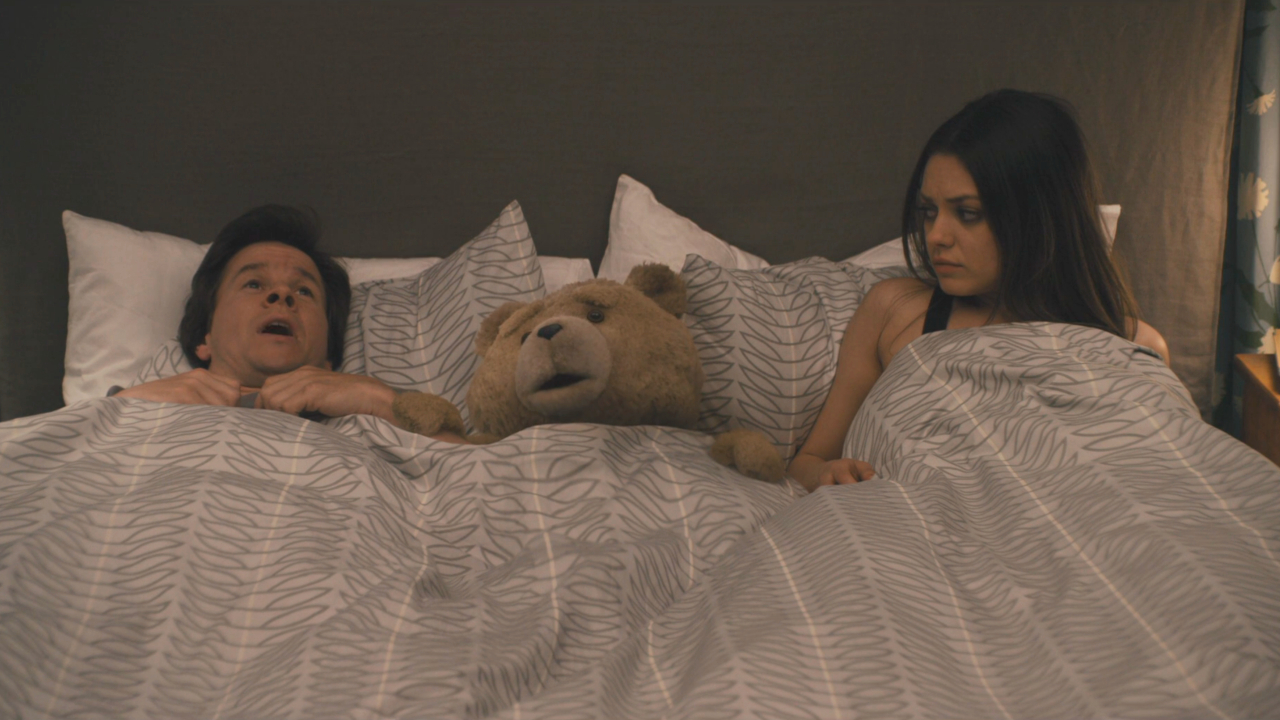 Mark Wahlberg and Ted lay in bed frightened, while Mila Kunis looks on in disbelief in Ted.