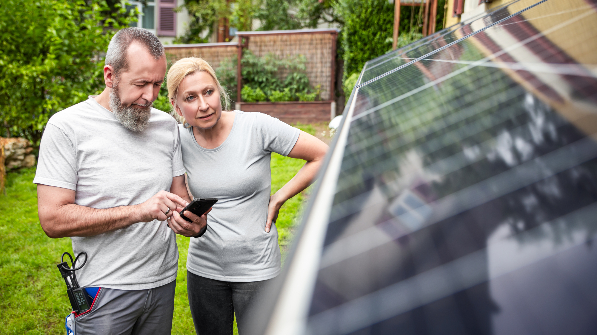 male and female stood in garden looking at wall mounted solar panels
