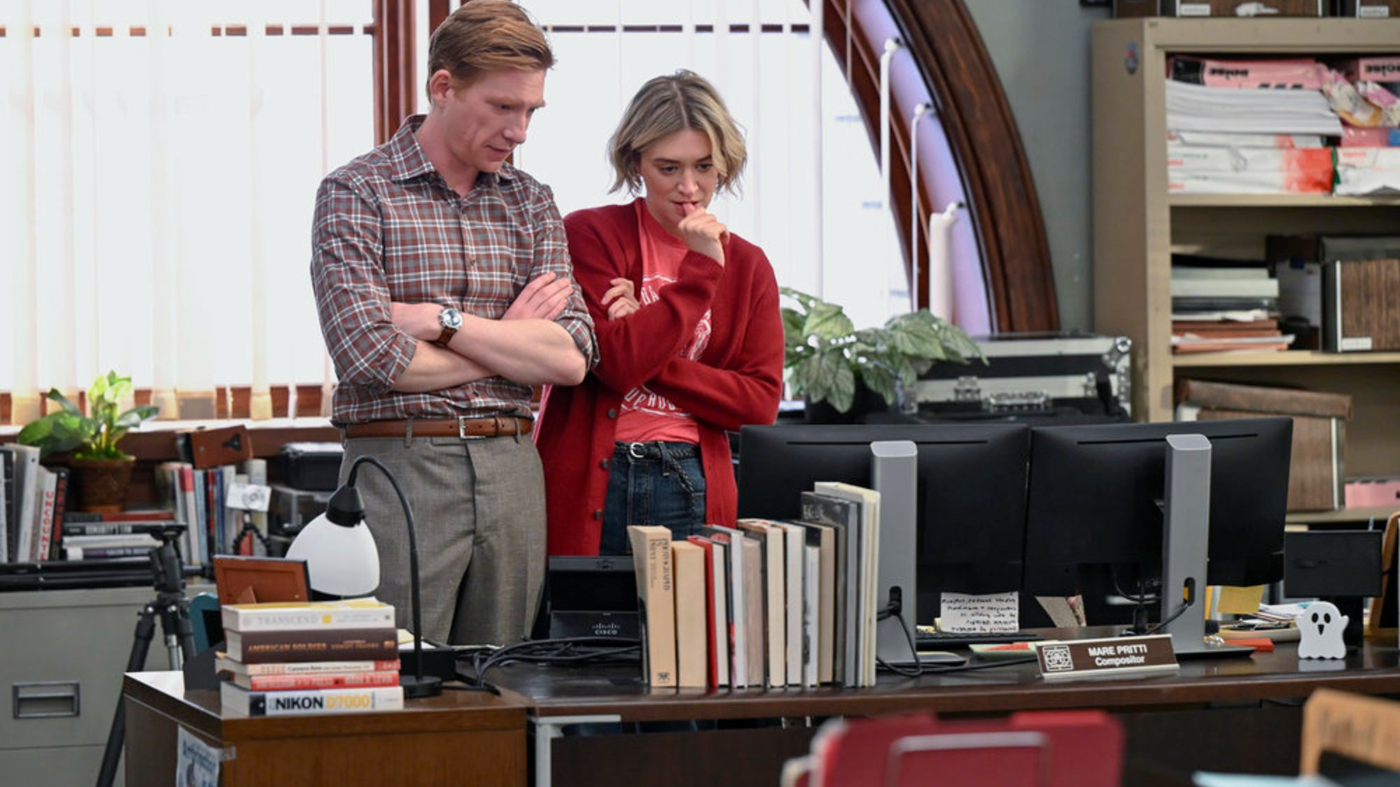 Chelsea Frei and Domhall Gleeson looking at the screen in The Paper.