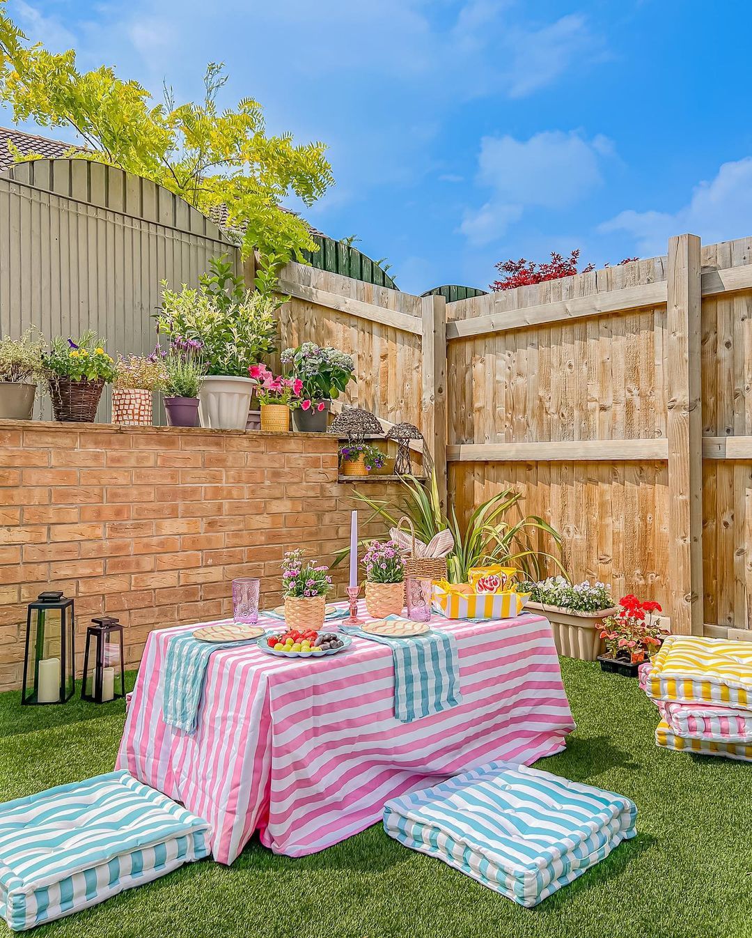 Meja outdoor dengan taplak meja warna-warni dan bantal