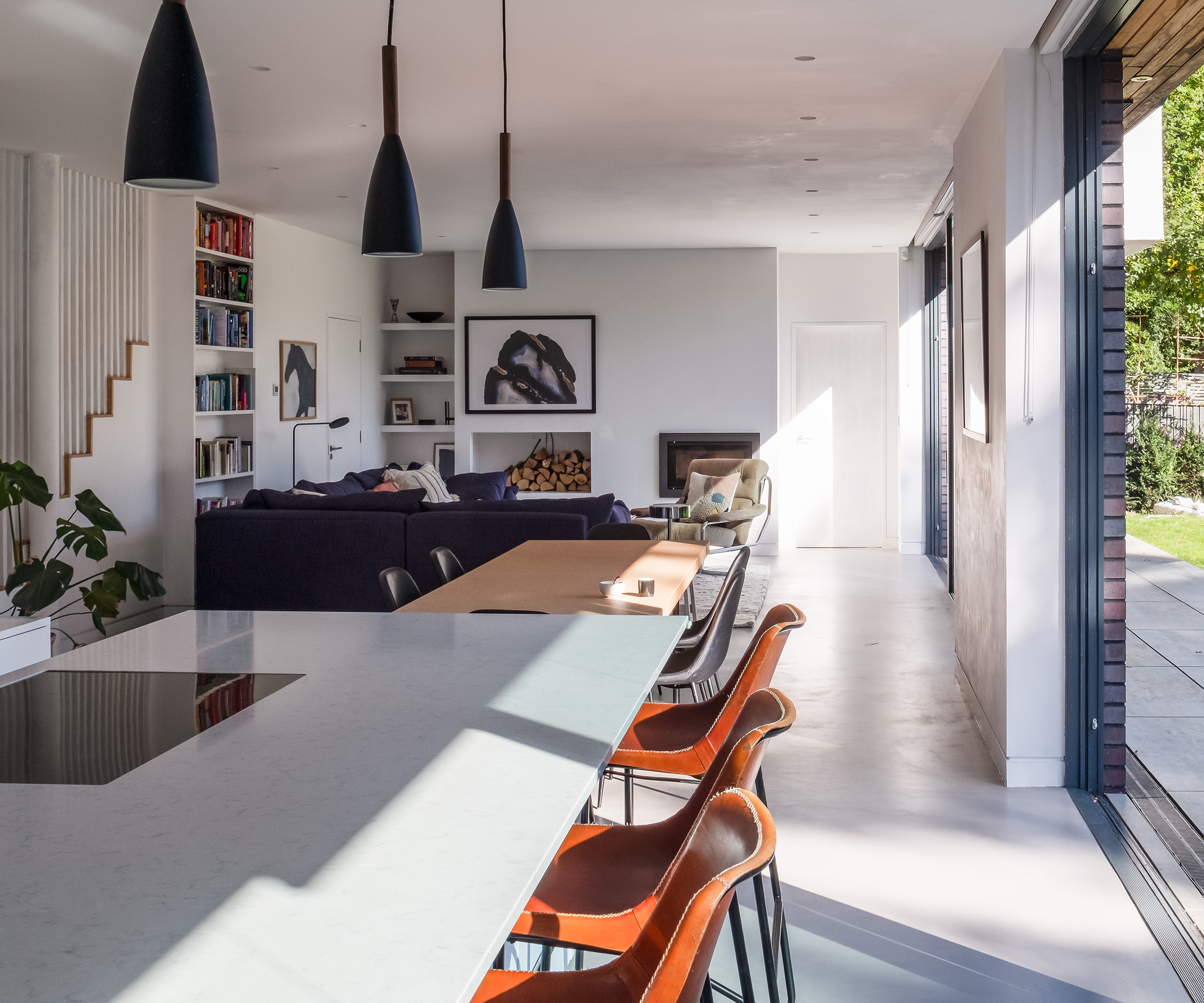 A long open plan living room, dining and kitchen area with sliding glass doors all along one side
