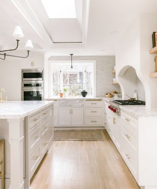 White kitchen base cabinets, skylight, marble countertop