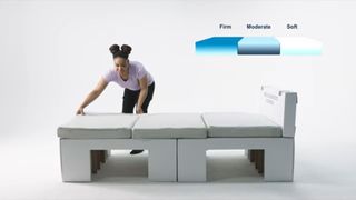 A woman assembles the Airweave Olympic mattress on a cardboard bed frame