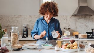 woman standing at her kitchen counter making granola with coconut oil
