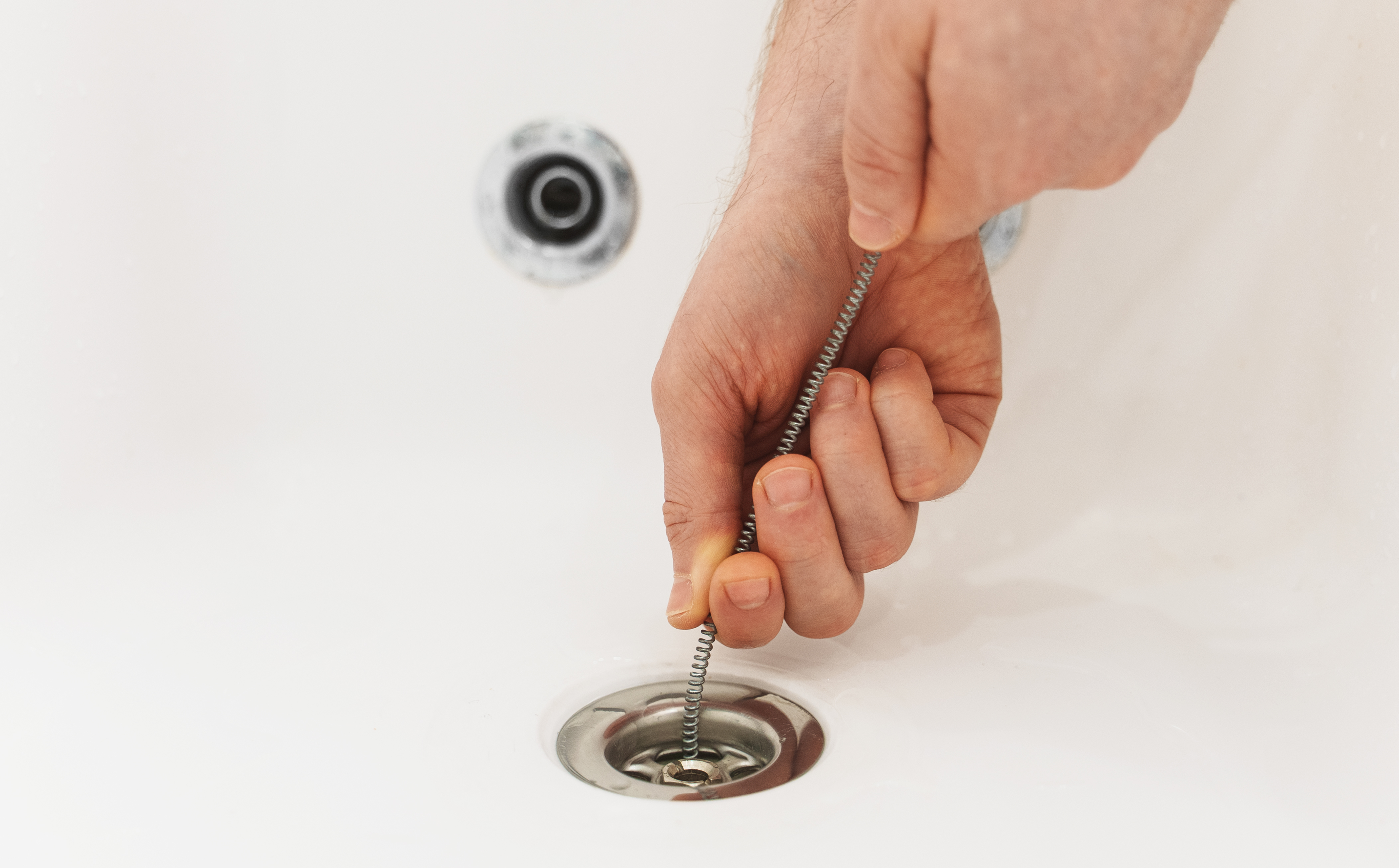 A drain snake being inserted into a drain