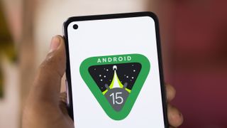 Android 15-logo op een smartphone in iemands hand