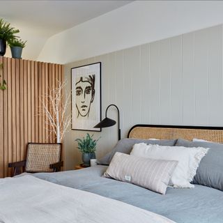 how to decorate a guest bedroom, neutral bedroom with wood paneling on one side and tongue and groove on the other, rattan bed, artwork, plants