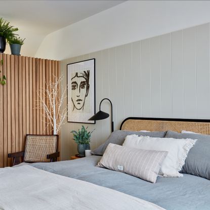 how to decorate a guest bedroom, neutral bedroom with wood paneling on one side and tongue and groove on the other, rattan bed, artwork, plants 