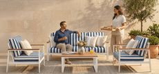 Photo of man and woman eating breakfast on striped patio sofa 