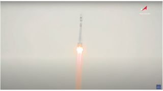 a white rocket rises into a foggy sky