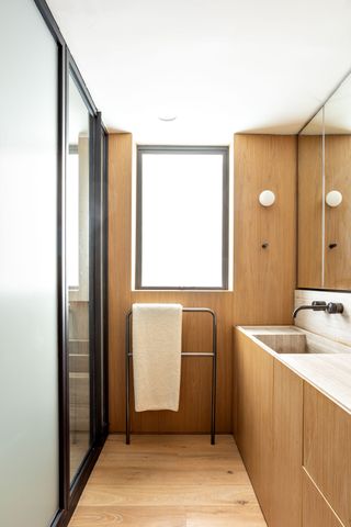 A bathroom in all wood, with a long railing to hang towels
