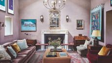 Large pink living room with fireplace, chandelier, artwork on walls, sofa, lounge chairs and ottoman